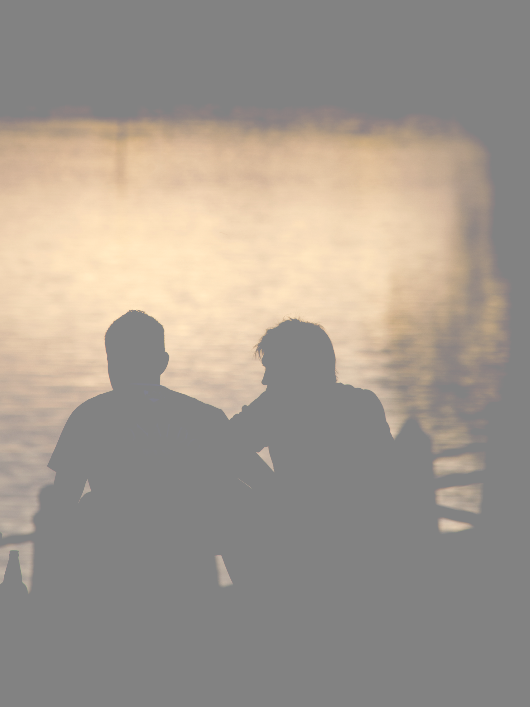 Two people sitting on a bench near water.